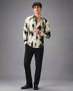 Man wearing a patterned shirt and black pants on a gray background